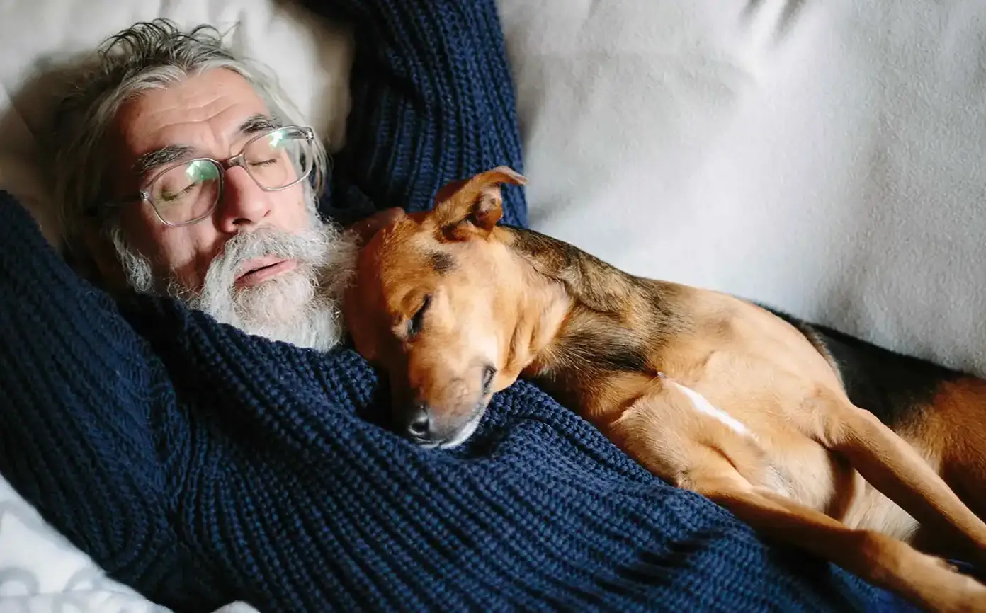 Older man sleeping comfortably with his dog
